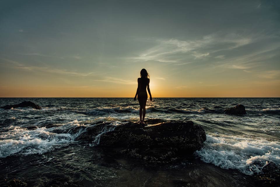 woman standing on a rock in the ocean